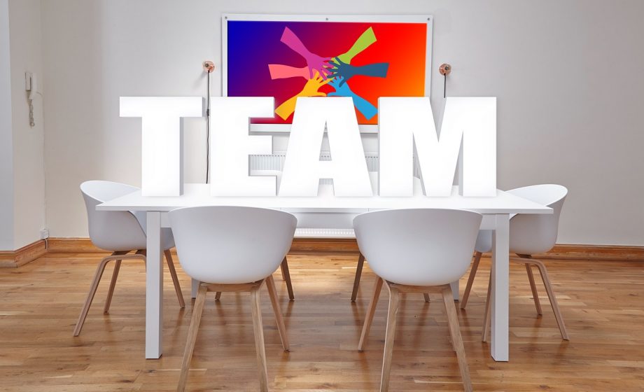 Teamleden van verschillende bureaus overleggen samen aan een vergadertafel