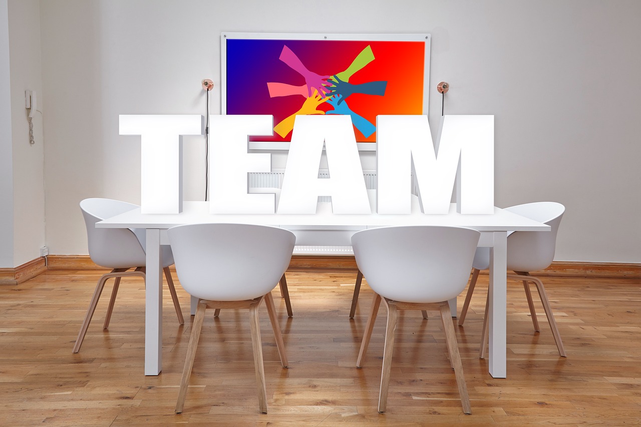 Teamleden van verschillende bureaus overleggen samen aan een vergadertafel
